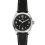The TUDOR Ranger wristwatch features a black dial with Super Luminova numerals at 12, 3, 6, and 9, a silver case, and a black textured strap with white stitching.