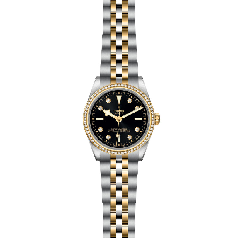 The TUDOR Black Bay One 36 S&G features a black dial, yellow gold hour markers, a gold bezel, and a two-tone silver and gold metal link bracelet.