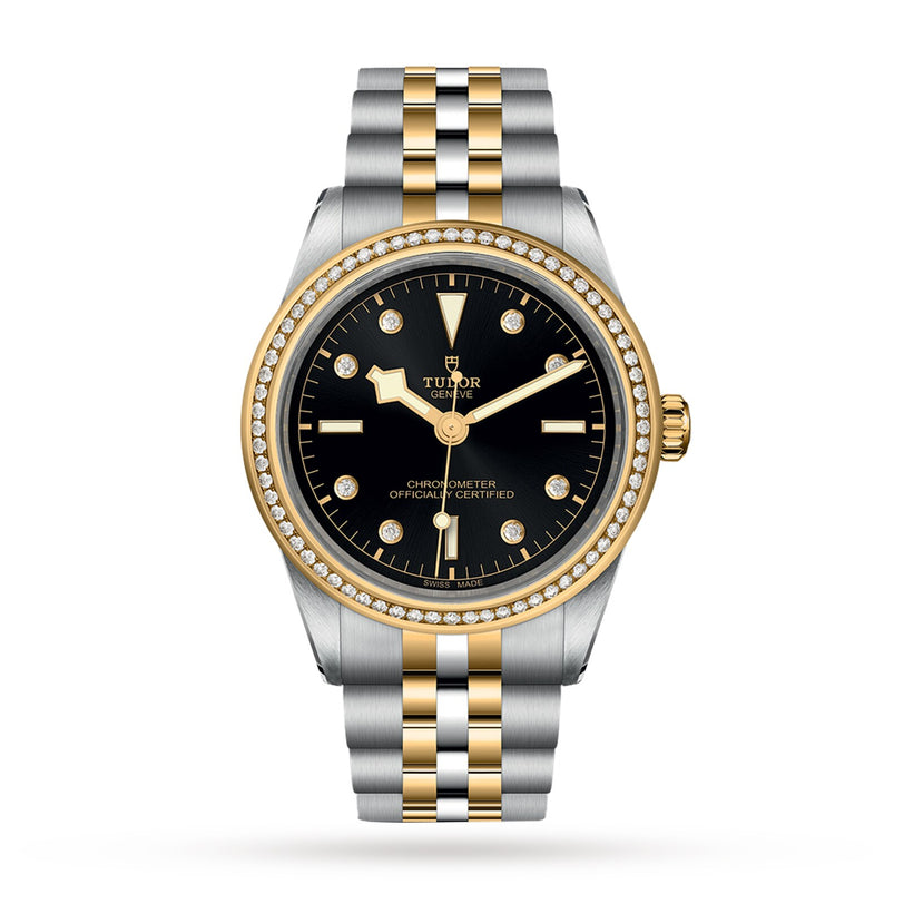 The TUDOR Black Bay One 39 S&G features a two-tone design with a black dial, yellow gold accents, diamond hour markers and bezel, a date window, and a metal link bracelet.