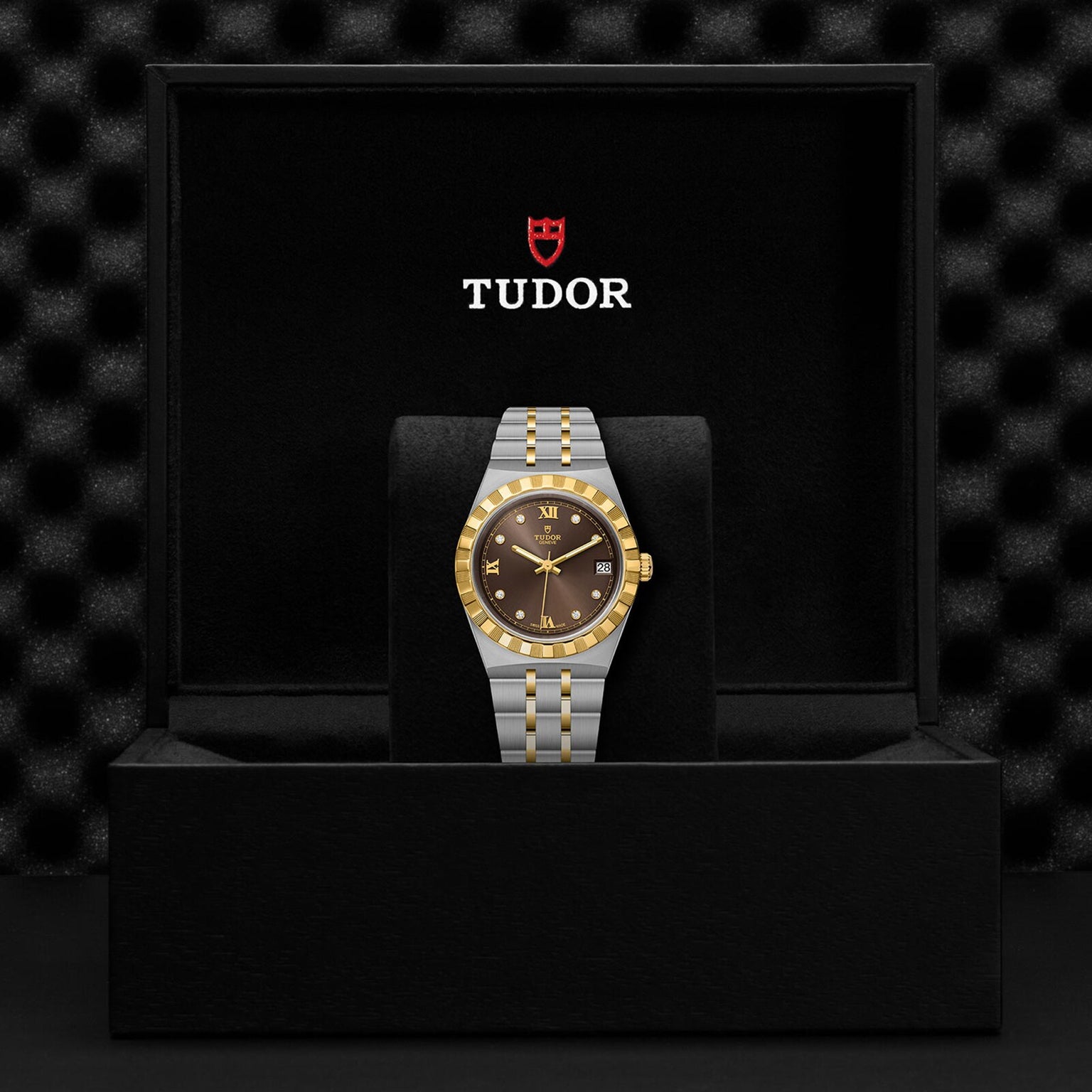 The TUDOR Royal wristwatch, featuring a gold bezel and black dial with automatic movement, comes in a sleek black TUDOR box—making a bold sport-chic statement.