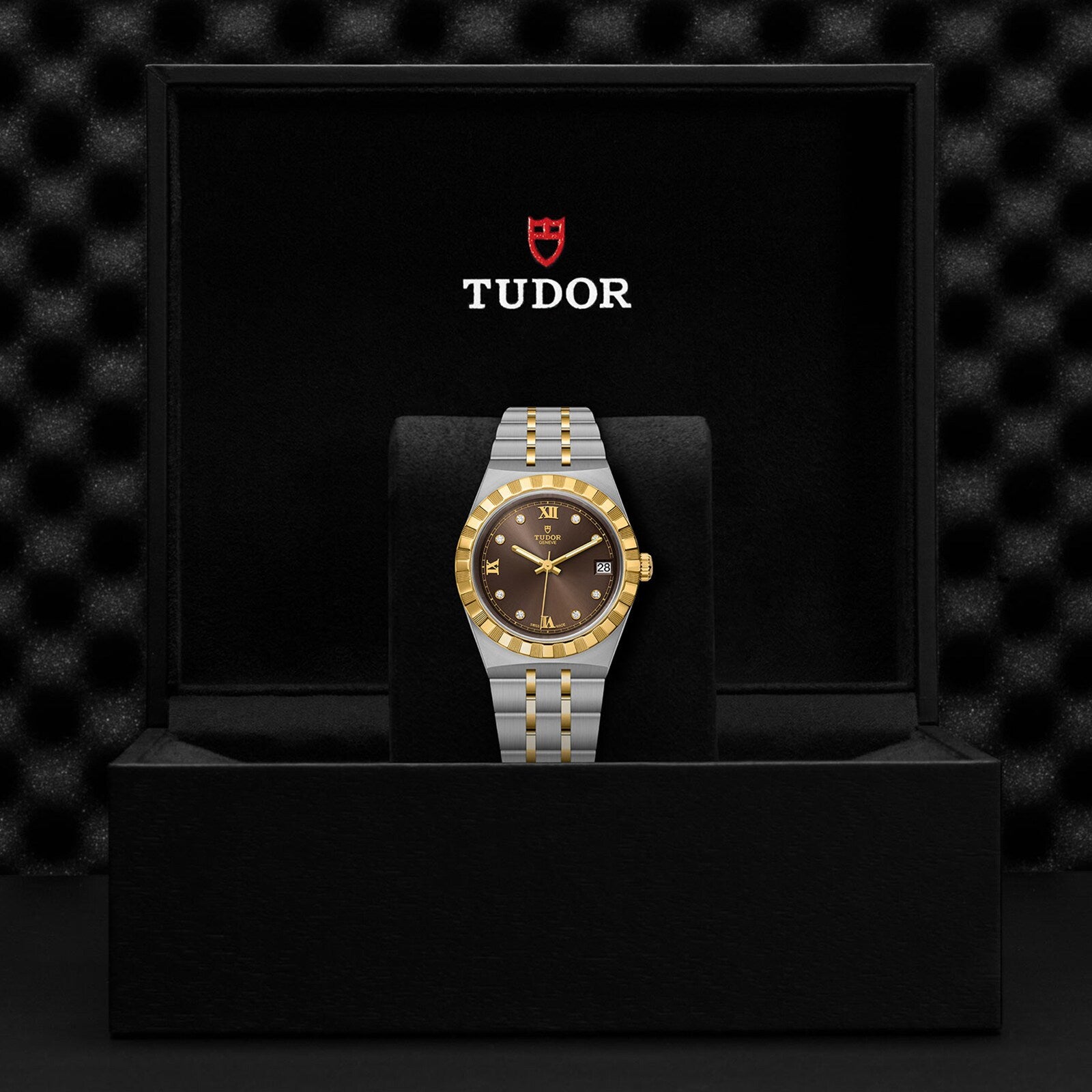 The TUDOR Royal wristwatch, featuring a gold bezel and black dial with automatic movement, comes in a sleek black TUDOR box—making a bold sport-chic statement.