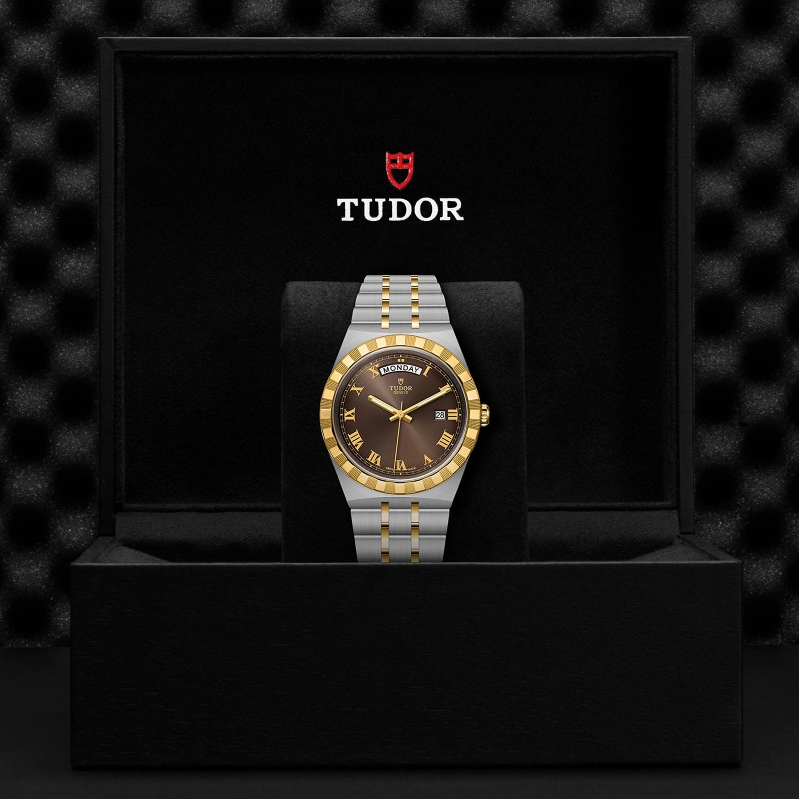 A TUDOR Royal wristwatch with a brown dial and two-tone silver and gold bracelet, featuring automatic movement, is presented in an open black TUDOR box.
