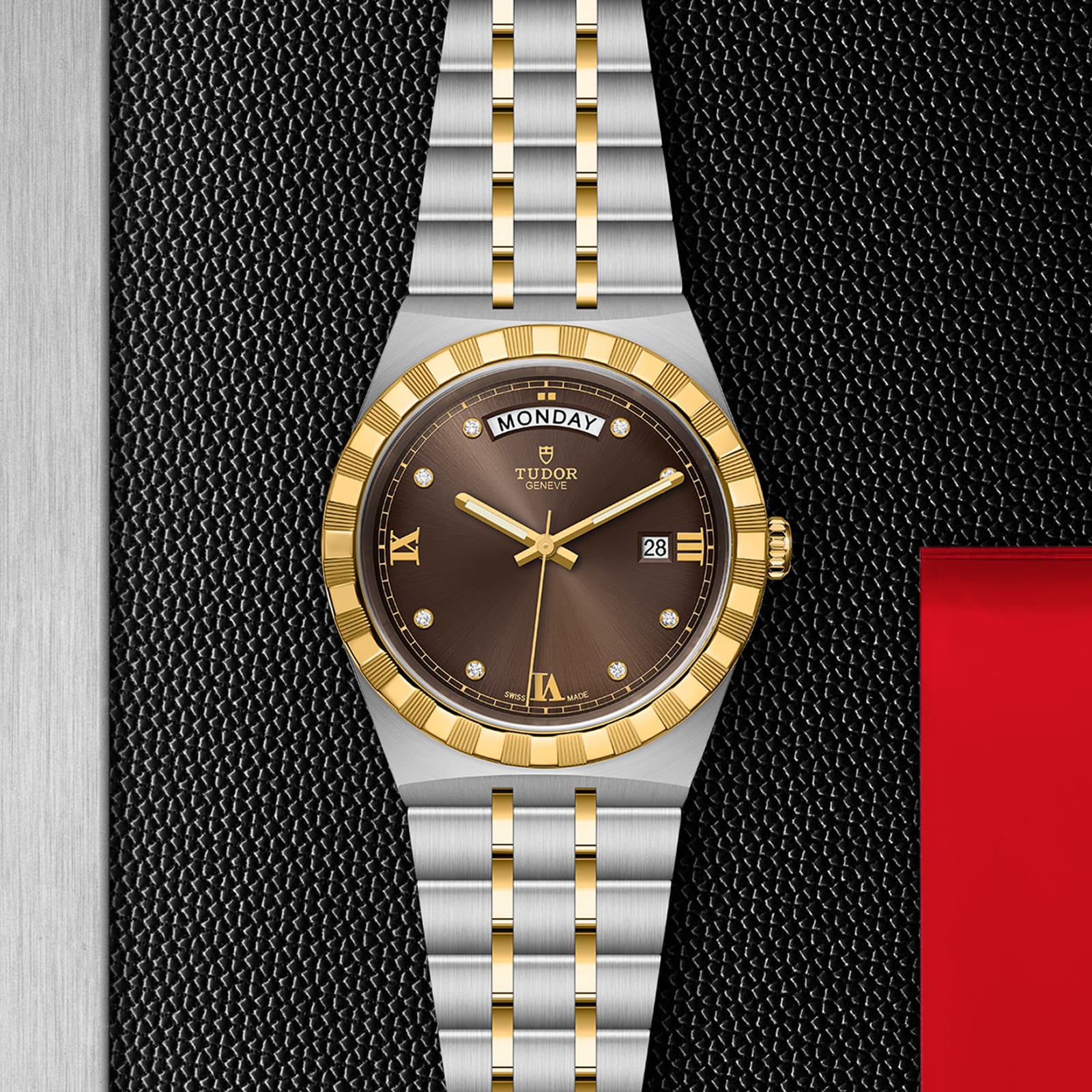 The TUDOR Royal is a sporty chic wristwatch featuring a gold and silver band, black dial with gold bezel, Roman numerals, diamond markers, automatic movement, and day-date displays on a textured black surface.