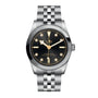 The TUDOR Black Bay 31 is a chic unisex watch with a stainless steel bracelet, black dial, gold accents, and round hour markers—shown stylishly against a white background.