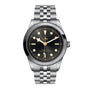 The TUDOR Black Bay One 41, a stainless steel wristwatch with a black dial, luminous markers, and metal bracelet, showcases unisex style and is photographed against a white background.