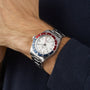 A TUDOR Black Bay GMT wristwatch with an opaline dial and red-blue bezel is worn on a person’s left wrist, visible against a dark long-sleeve shirt.