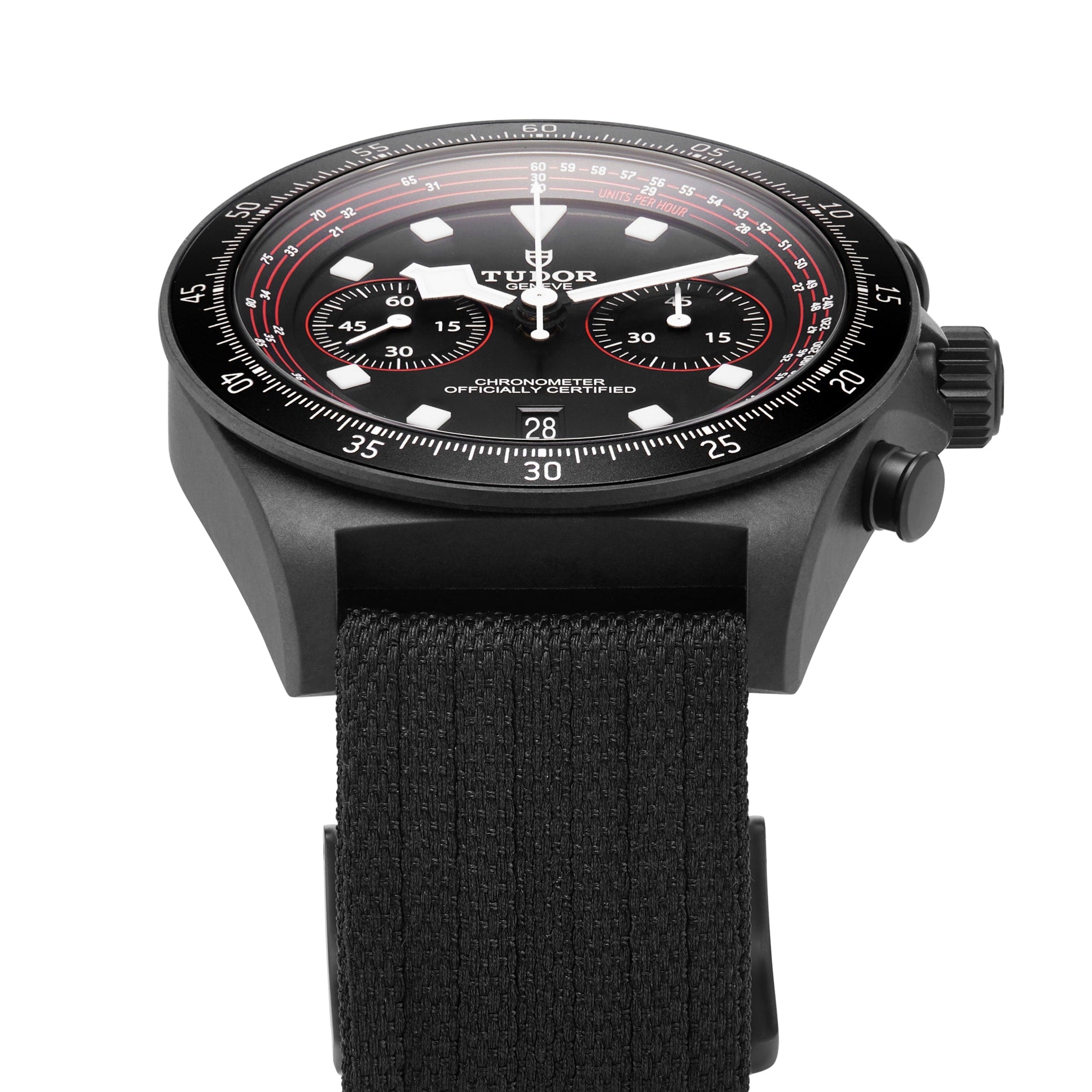 Close-up of a TUDOR Pelagos FXD Chrono wristwatch with a black case, black fabric strap, and black dial featuring red and white accents, three subdials, and a cycling-specific tachymeter scale.
