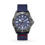 A TUDOR Pelagos FXD wristwatch featuring a blue dial, white hour markers, black bezel, and a blue fabric strap with red stripe, known for underwater navigation functions, shown on a white background.