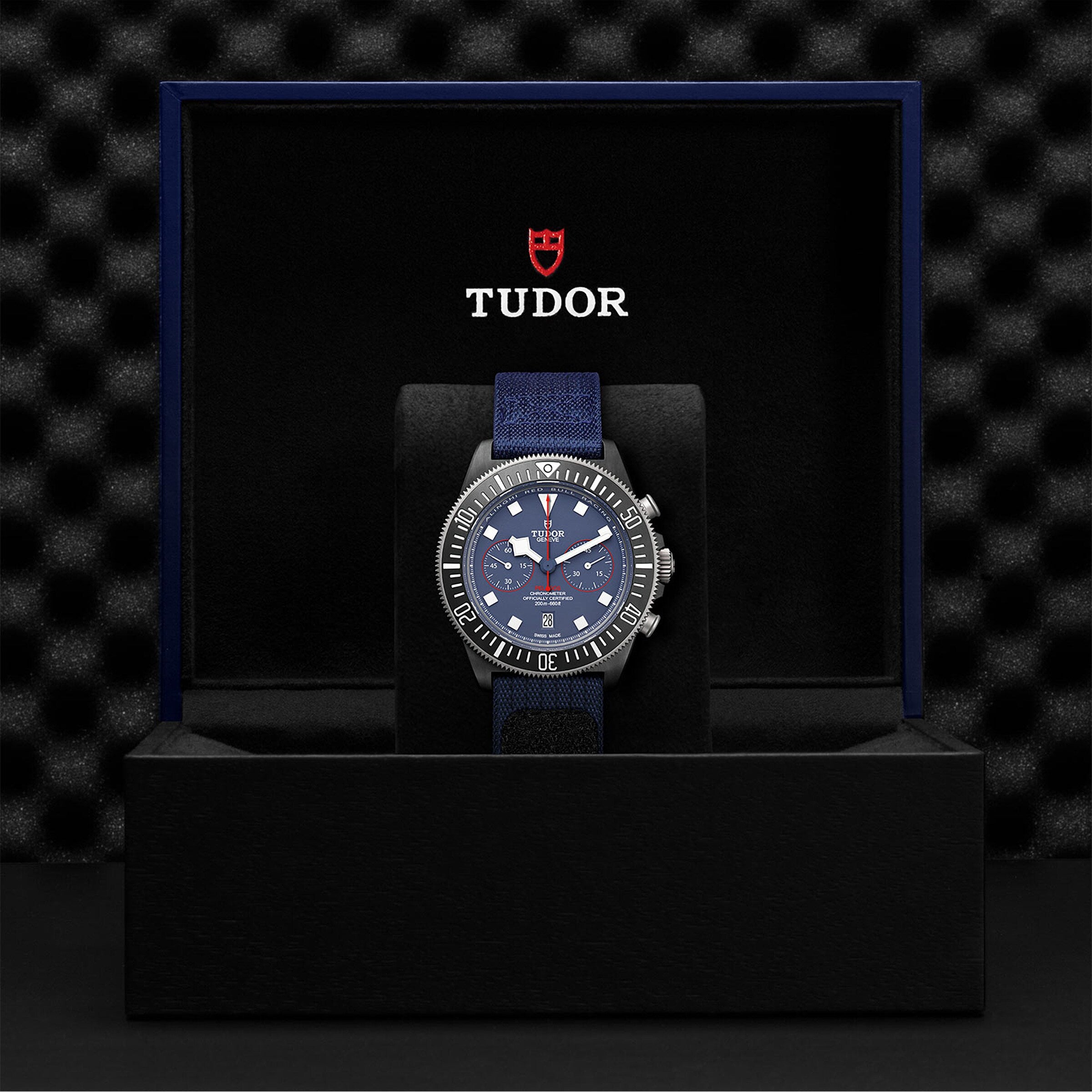 The TUDOR Pelagos FXD Chrono, inspired by the French Navy and built for underwater navigation, features a blue strap and dial, presented elegantly in a black TUDOR-branded watch box.