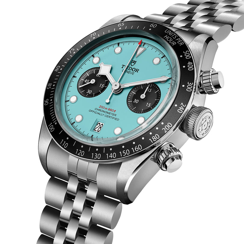 The TUDOR Black Bay Chrono is a stainless steel wristwatch with a turquoise dial, black bezel, silver bracelet, subdials, date display, and Swiss Chronometer Manufacture Calibre movement.