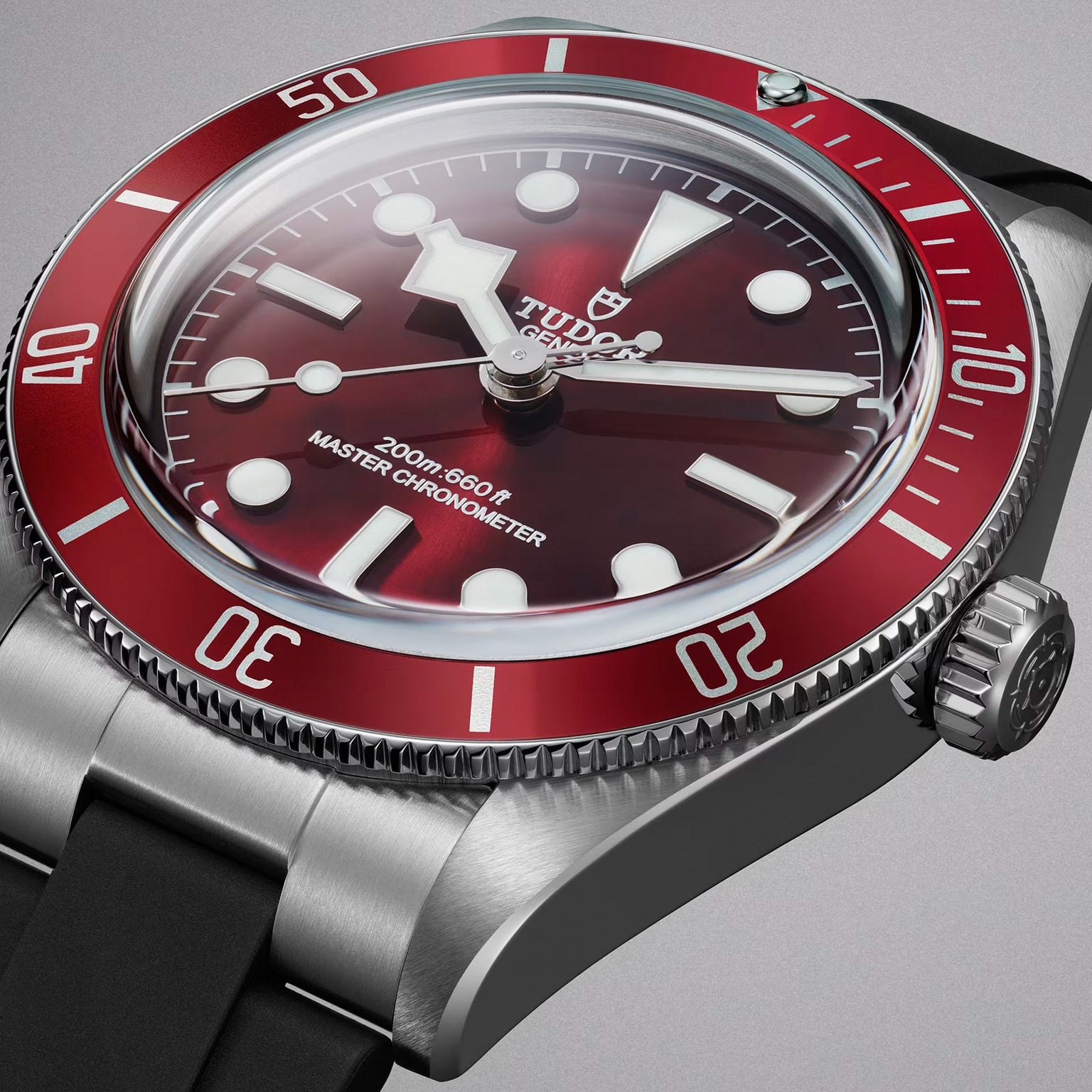 Close-up of the TUDOR Black Bay 58 wristwatch featuring a red bezel, burgundy dial, and black rubber strap on a gray background.