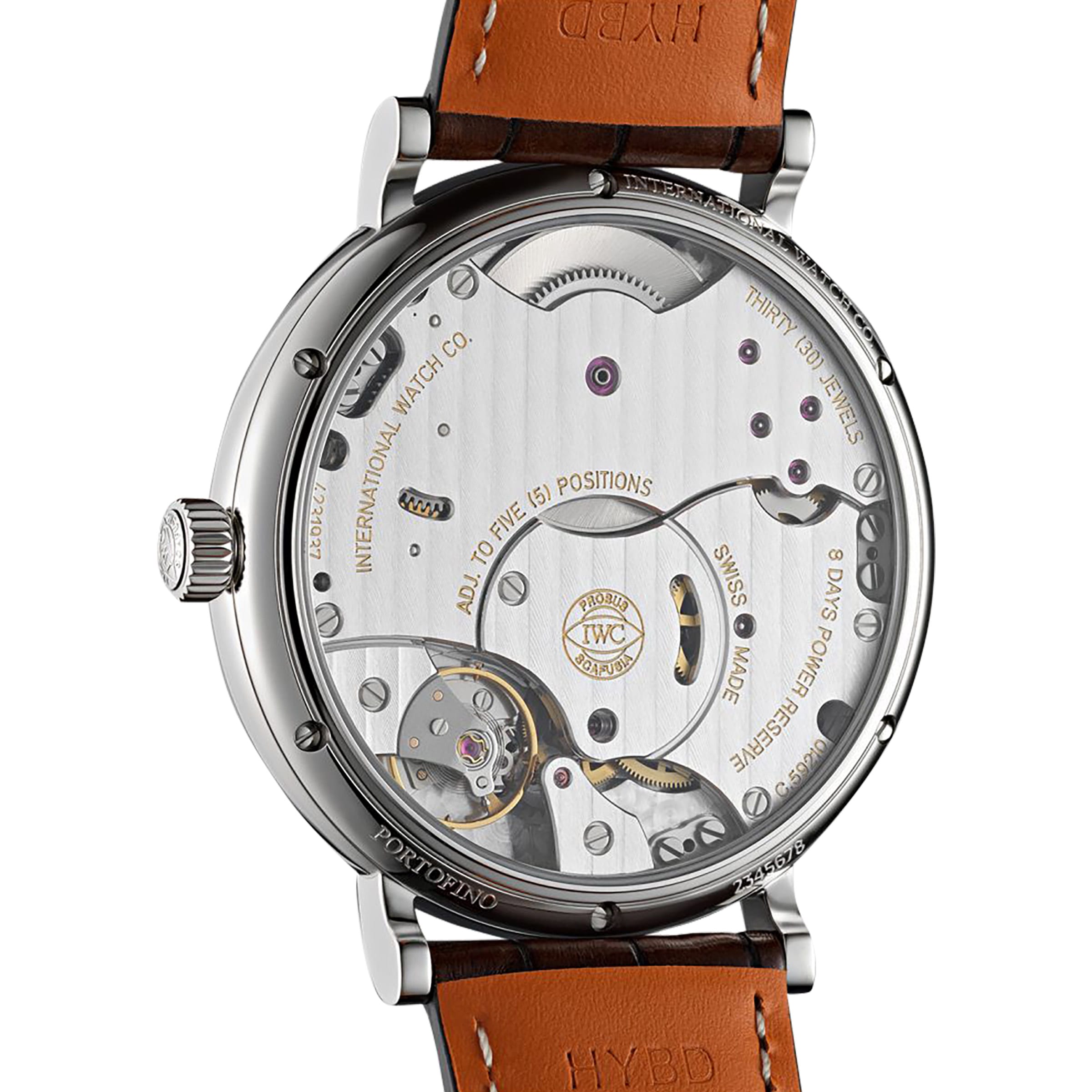 Close-up of the IWC Schaffhausen Portofino Hand-Wound Eight Days, revealing its intricate exposed gears, detailed engravings, and a brown leather strap.