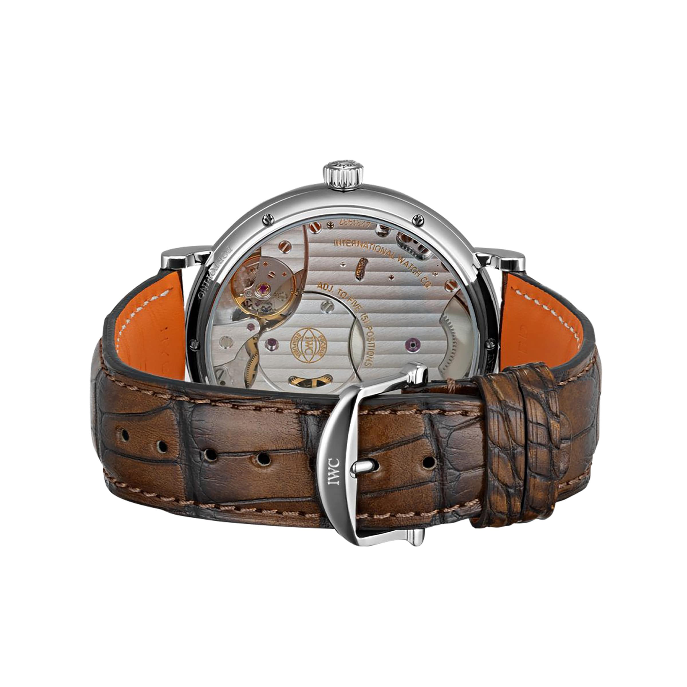 The IWC Schaffhausen Portofino Hand-Wound Eight Days features a brown leather strap, a silver buckle engraved with IWC, and an exhibition caseback revealing the IWC-manufactured calibre.