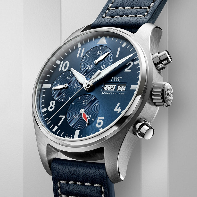 The IWC Schaffhausen Pilots Watch Chronograph 41 features a stainless steel case, blue dial with three subdials, day and date display, and a blue leather strap with white stitching.