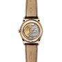 The Patek Philippe Complication 5396R-011 is a luxury watch featuring a brown leather strap and a transparent back that displays its intricate mechanical movement.