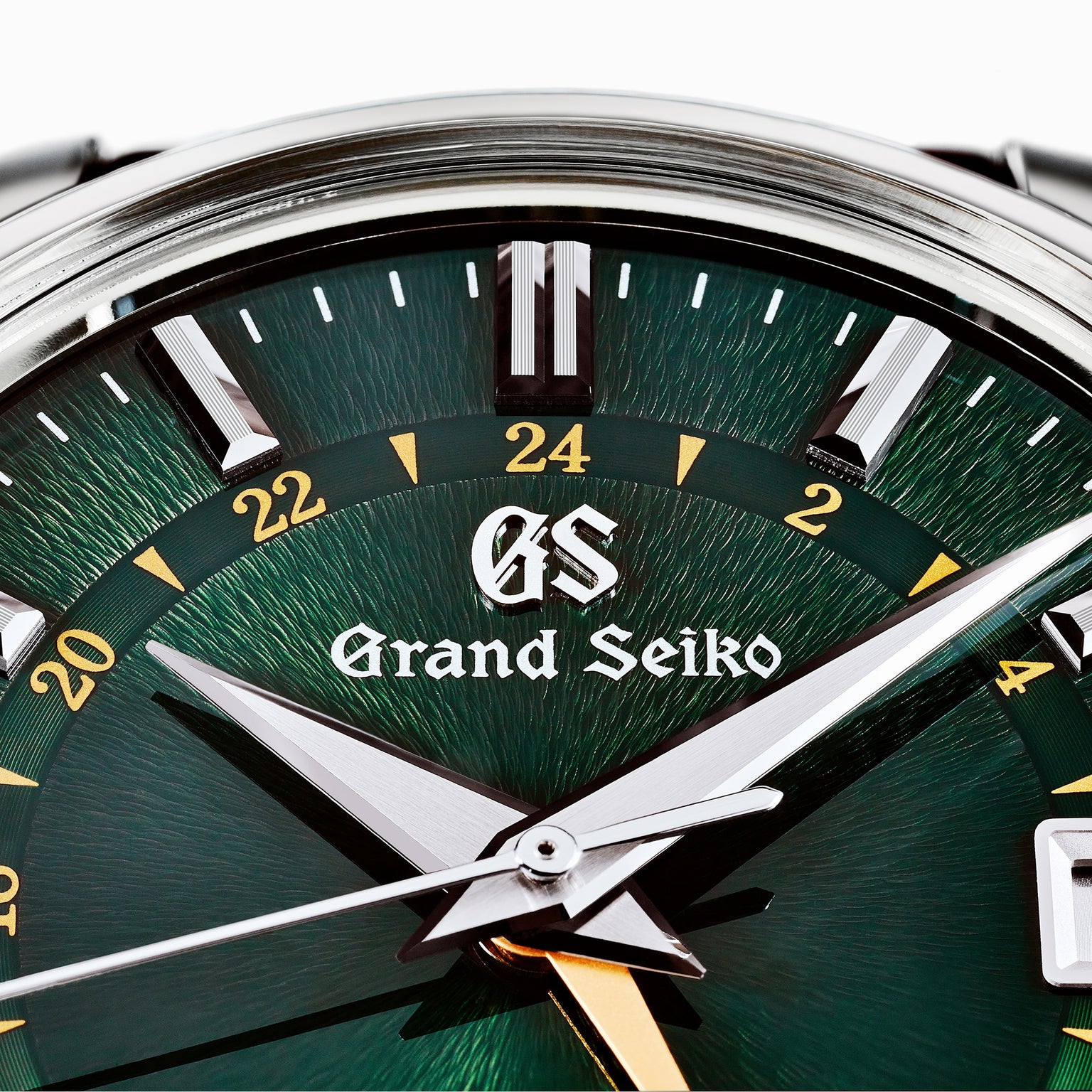 Close-up of the Grand Seiko Automatic GMT Elegance watch face, showcasing a British Racing Green sunburst dial inspired by Mount Iwate, silver hands, a gold GMT hand, sharp hour markers, and the Grand Seiko Standard logo.