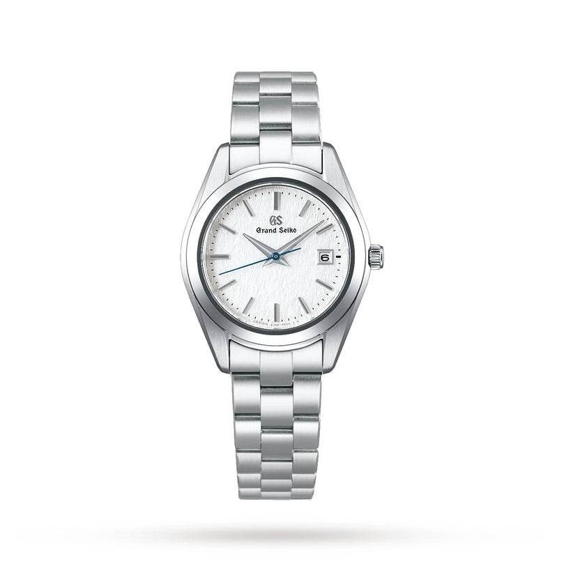 The Grand Seiko Ladies Heritage features a stainless steel case, white textured dial, silver hour markers, blued seconds hand, date at 3 o’clock, and a mirror-finished metal link bracelet.