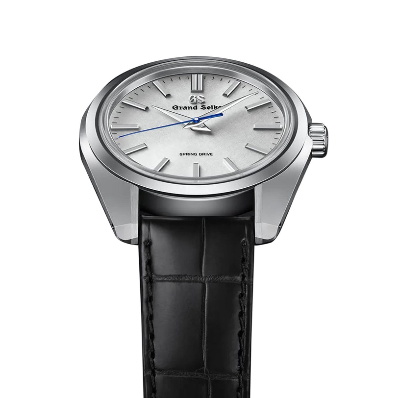 The Grand Seiko Spring Drive Heritage is a 44GS wristwatch with a silver dial, silver markers and hands, a blue second hand powered by Spring Drive, and comes on a black leather strap.