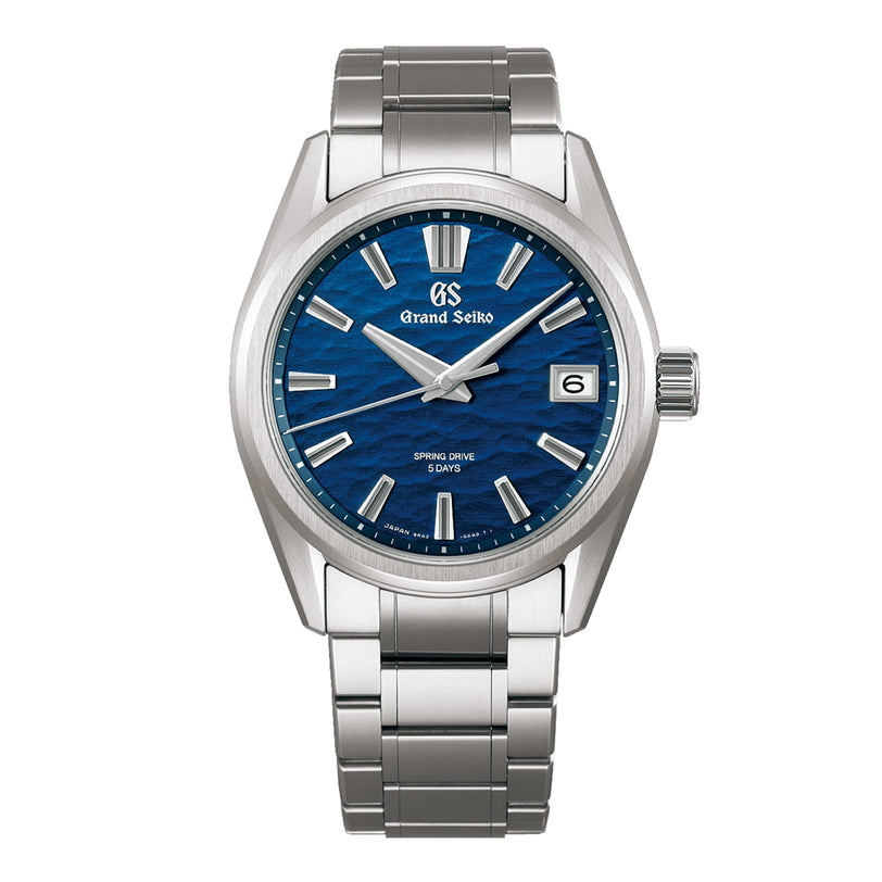 The Grand Seiko Spring Drive 5 Days Evolution 9 wristwatch features high-intensity titanium, a blue textured dial, silver hour markers, date window at 3 o’clock, and a polished metal bracelet.