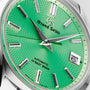 A close-up of the Grand Seiko Hi-Beat Limited Edition Heritage watch with a vibrant green textured dial, silver hour markers and hands, date window at 3 o’clock showing 6, powered by the precise 9S85 calibre automatic movement.