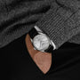 A person in a gray sweater and black pants has their hand in their pocket, showcasing the Grand Seiko Manual Hi-beat 80 Hours Evolution 9 wristwatch with a silver dial and black leather strap.