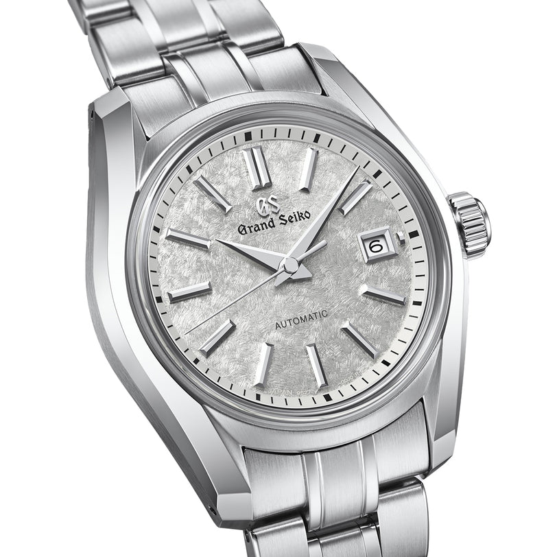 The Grand Seiko Ladies Automatic Heritage features a textured silver dial with silver hour markers, a date window at 3 o’clock, and a stainless steel bracelet with Zaratsu polishing inspired by the iconic 62GS.