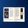 An open HODINKEE Magazine, Volume 9 by Hodinkee sits on a blue surface, featuring articles and photos of luxury watches, such as close-ups of rectangular masterpieces with leather straps.