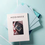 HODINKEE Magazine, Volume 9 by Hodinkee rests on light blue and teal folders, showcasing a wristwatch on the cover and celebrating horology against a light blue background.