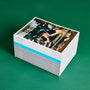 A neatly arranged stack of Hodinkee magazines rests on a green surface, topped by HODINKEE Magazine, Volume 11, which features a person inspecting a watch through a magnifying loupe.