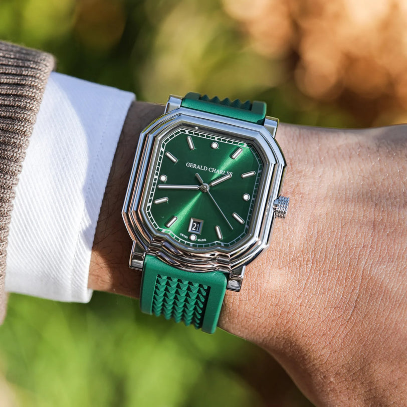 Someone wears the Gerald Charles Maestro 2.0 Ultra-Thin, featuring a stainless steel case, emerald green sunburst dial with geometric design, and a matching rubber strap, showing both time and date.