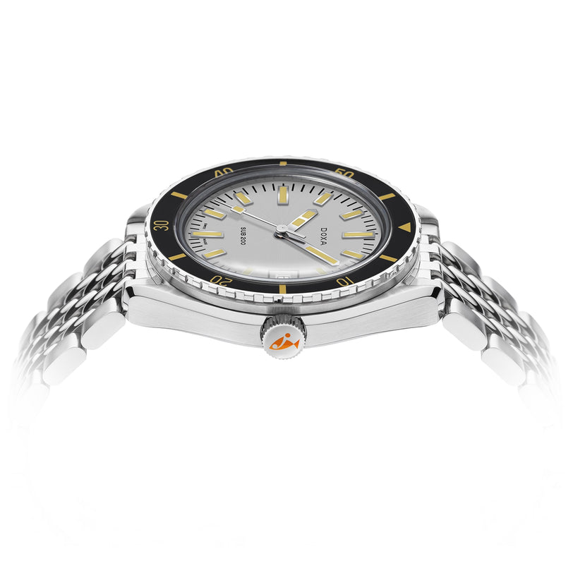 The DOXA Sub 200 Searambler, a stainless steel divers watch with a black and yellow rotating bezel, silver dial, and metal bracelet, is displayed at an angle on a white background.