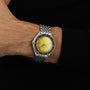 A person wearing a DOXA Sub 200 Divingstar with a yellow face and metal band on their left wrist, dressed in a long-sleeved black shirt.