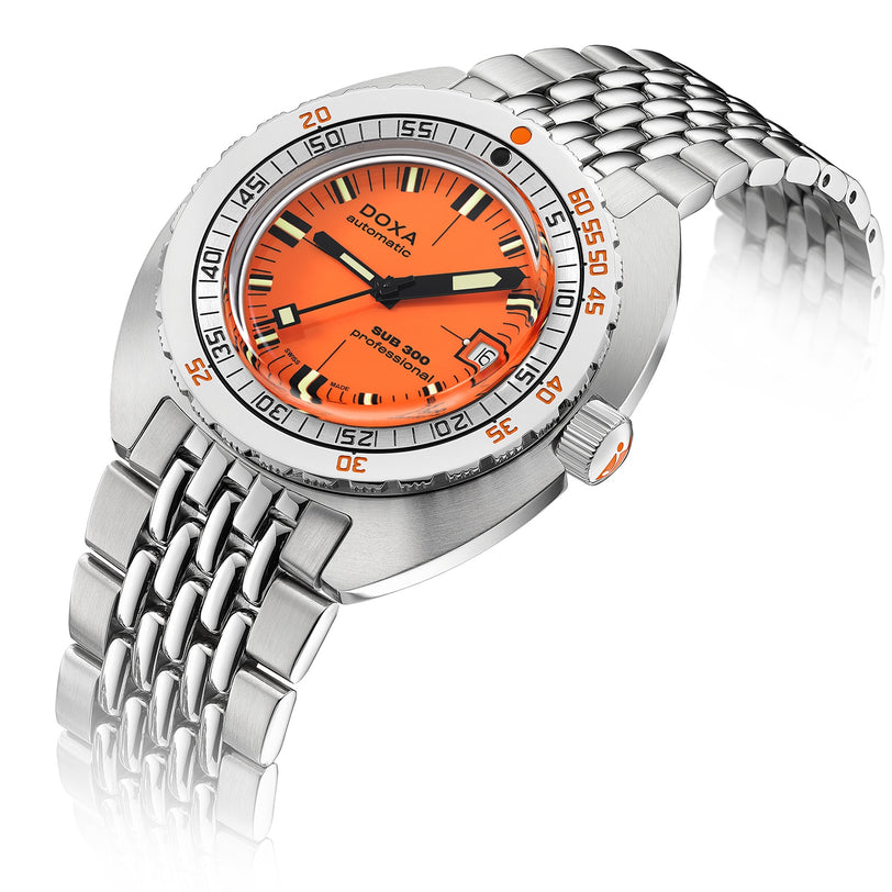 The DOXA Sub 300 Professional is a stainless steel divers watch featuring an orange dial, unidirectional bezel, date display at 3 o’clock, and silver metal bracelet, displayed at an angle against a white background.