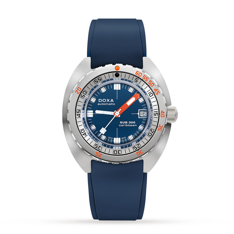 The DOXA Sub 300 Caribbean is an automatic divers watch with a round silver case, unidirectional bezel, blue dial with date display, and blue rubber strap, shown against a plain white background.
