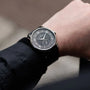 A person wearing a Louis Erard Petite Seconde Guilloché Anthracite Black wristwatch with a dark dial and silver hour markers on their left wrist.