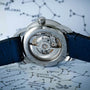 Close-up of the Louis Erard Petite Seconde Malachites transparent back, revealing its inner mechanism and paired with a blue leather strap.