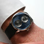 The Louis Erard Le Régulateur Louis Erard x Cédric Johner Blue is a wristwatch with two overlapping dials on a black leather strap, shown worn on a persons wrist.