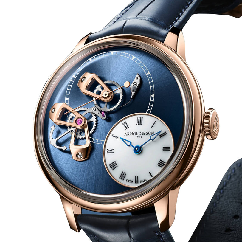 Close-up of the Arnold & Son DSTB 42 Red Gold, an elegant blue and gold wristwatch featuring exposed gears and a small white Roman numeral dial.