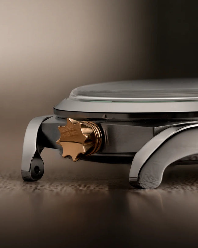 40mm titanium watch with brown dial, frog-shaped bronze crown, black bezel, and white lugs on neutral background.