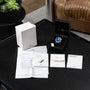An IWC Schaffhausen Aquatimer Cousteau Divers Limited Edition with a blue dial, complete with box, paperwork, manuals, and packaging displayed on a black table.