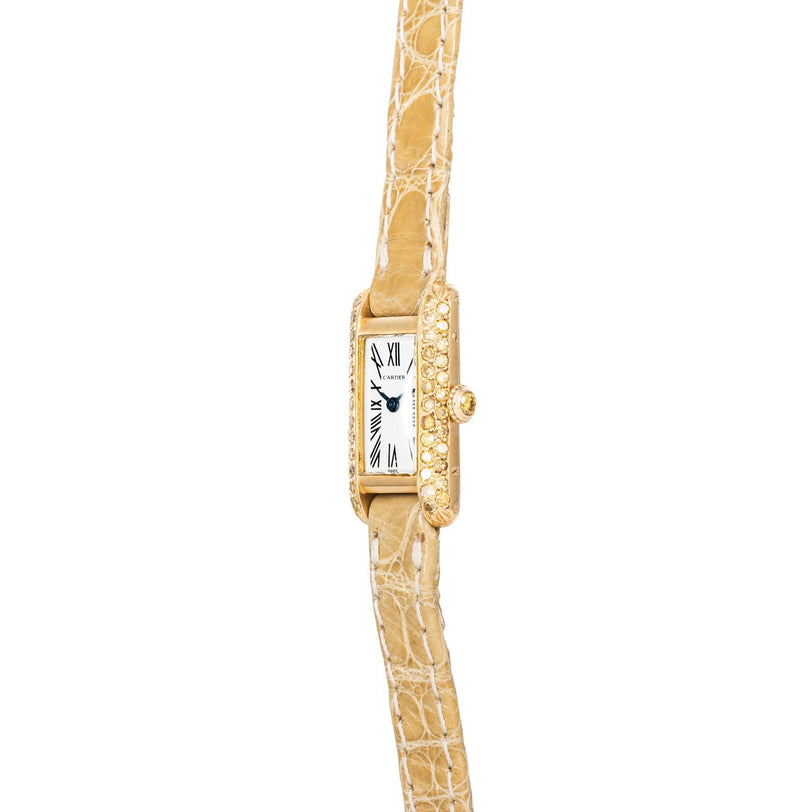The Cartier Tank is a gold rectangular wristwatch featuring a textured beige leather strap and diamond-accented case.