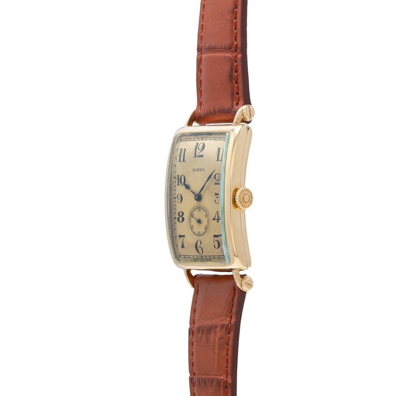 The Patek Philippe Birks Rectangular Dress Watch features a gold rectangular face and brown leather strap, displayed from a side angle.