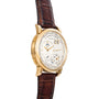 The Lange & Sohne Lange 1 Timezone is a gold luxury wristwatch with a brown leather strap and a white face featuring multiple dials and indicators.