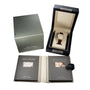 The Lange & Sohne Lange 1 Timezone luxury watch is shown in a display box, accompanied by a green outer box and two booklets stored in a leather folder.