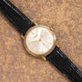 The Patek Philippe Calatrava Waterproof wristwatch with a black leather strap rests on a textured brown surface.