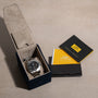 A Breitling Avenger II Seawolf watch in its open box, accompanied by manuals and a leather card holder on a beige surface.