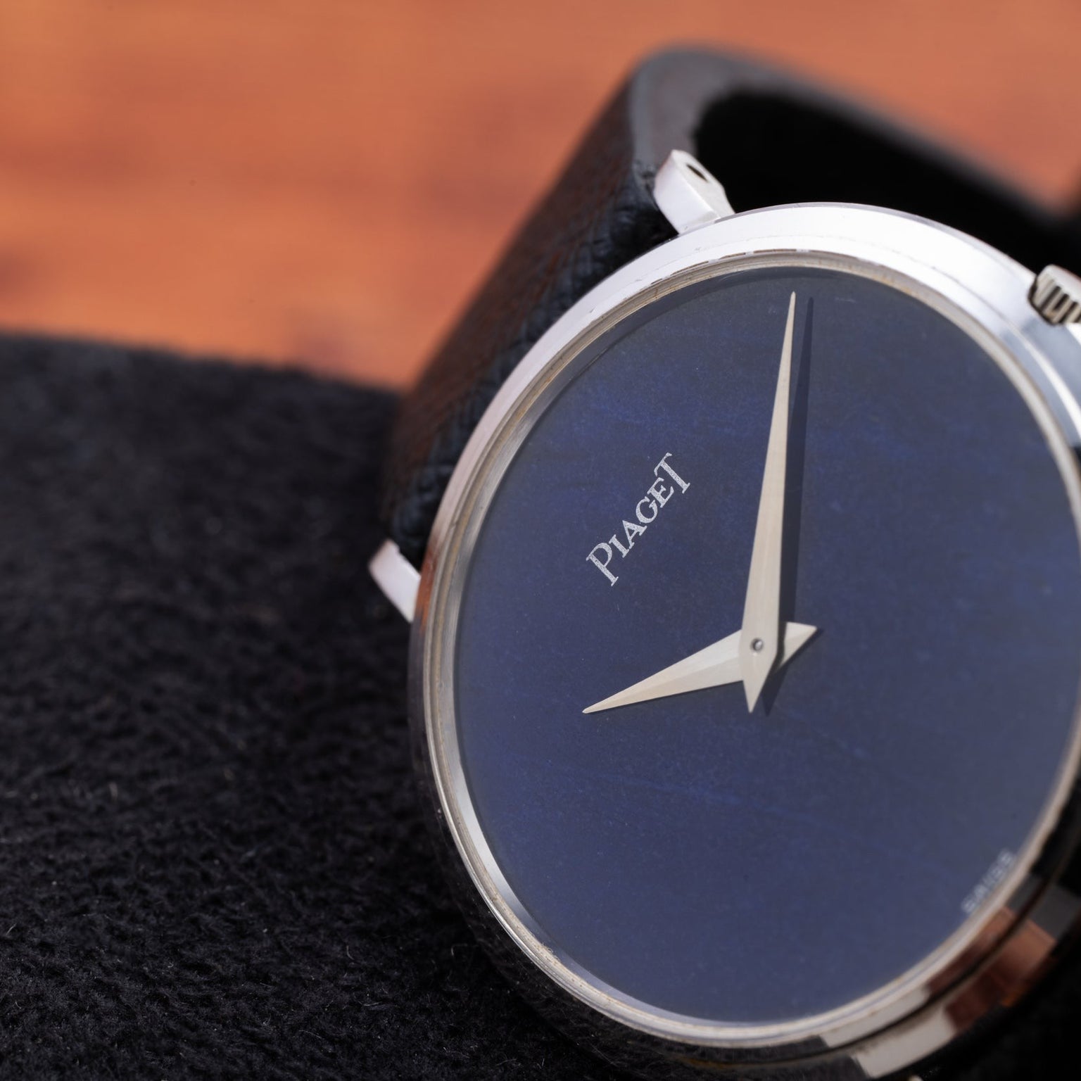 Close-up of the Piaget Ladies Lapis Lazuli Dress Watch, featuring a blue lapis lazuli dial and silver hands, displayed on a black textured surface.