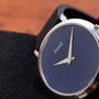 Close-up of the Piaget Ladies Lapis Lazuli Dress Watch, featuring a blue lapis lazuli dial and silver hands, displayed on a black textured surface.