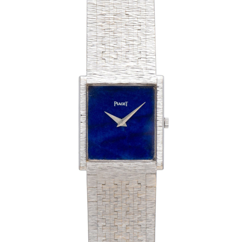 A Piaget White Gold Lapis Lazuli Dress Watch with a square blue face and textured metal band is displayed on a white background.