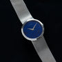A White Gold Lapis by Piaget wristwatch from Cartier featuring a blue face and silver hands, set against a black background.
